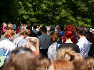 Bild vergrößern: Menschengetümmel im Park. Eine dichte Menschenmenge lässt auf ein öffentliches Ereignis schließen.